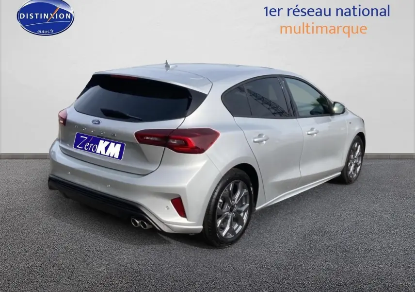 Ford Focus 2025 gris en 3/4 arrière droit avec jantes alu 17 pouces et double échappement sport.
