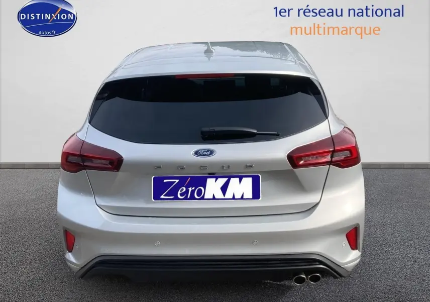 Vue arrière d'une Ford Focus gris clair 2025 avec double pot d'échappement et vitres arrière surteintées.