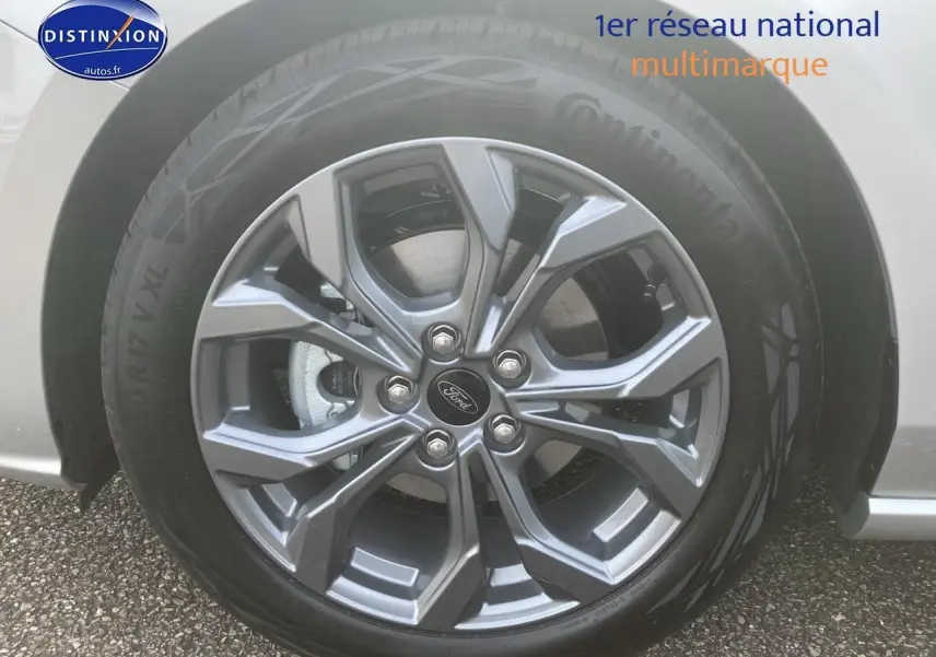 Gros plan sur la jante alu 17 pouces gris foncé d'une Ford Focus gris clair, avec logo Ford au centre.