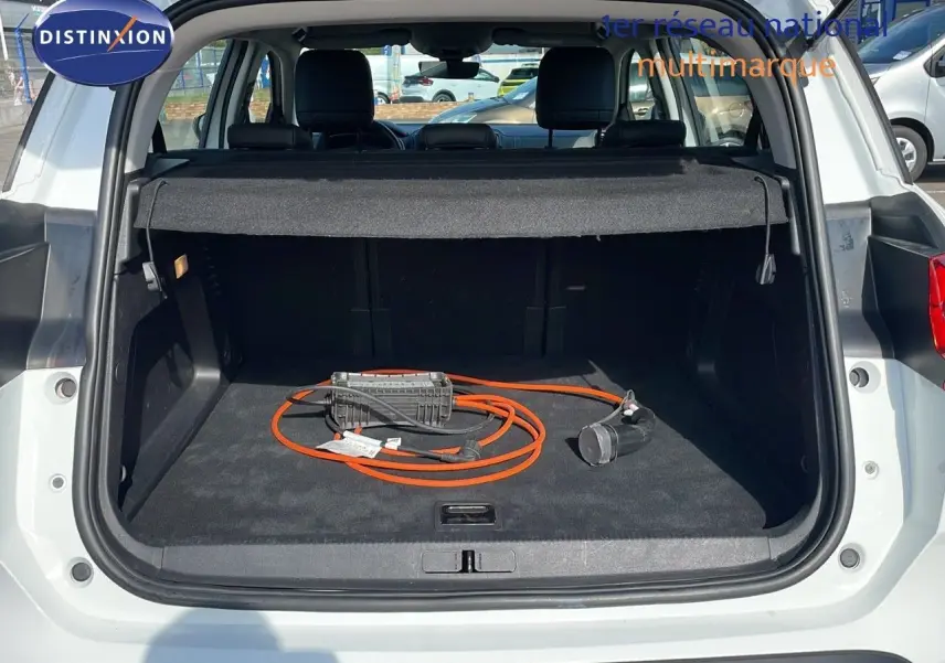 Coffre ouvert d'un Citroën C5 Aircross blanc nacré, montrant un câble de recharge orange pour hybride plug-in.