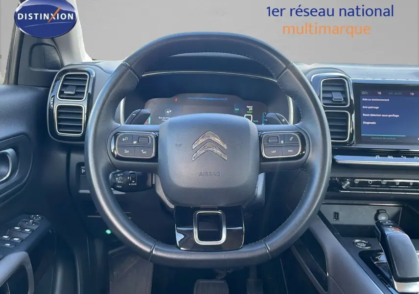 Vue rapprochée du volant noir et du tableau de bord digital du Citroën C5 Aircross blanc nacré hybride 2021.