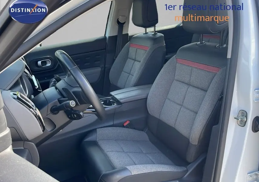 Vue intérieure côté conducteur du Citroën C5 Aircross blanc nacré, sièges gris tissu et cuir noir avec bande rouge.