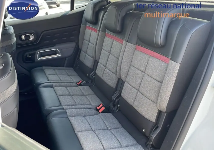 Vue intérieure des sièges arrière du Citroën C5 Aircross blanc nacré, avec sellerie tissu gris et cuir noir à surpiqûres rouges.