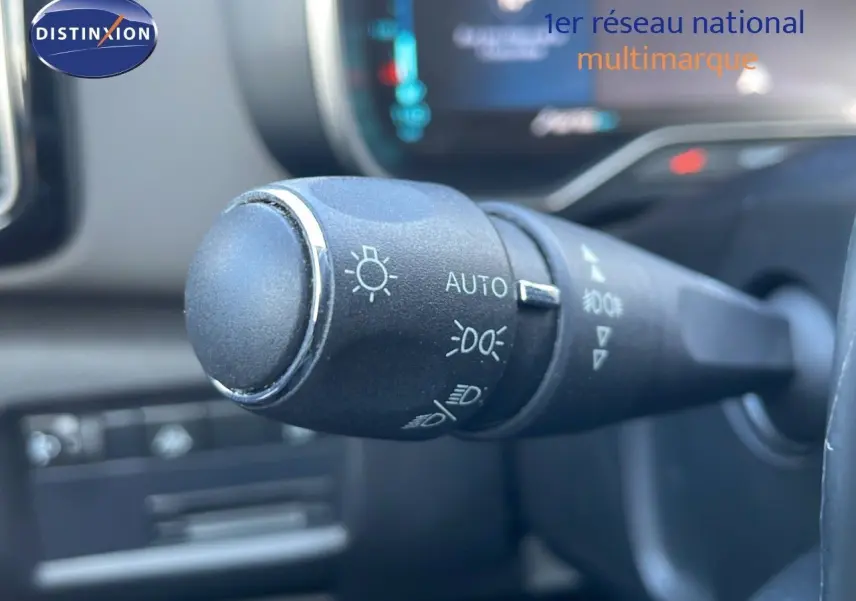 Gros plan sur la commande des phares du Citroën C5 Aircross blanc nacré hybride, intérieur noir moderne.