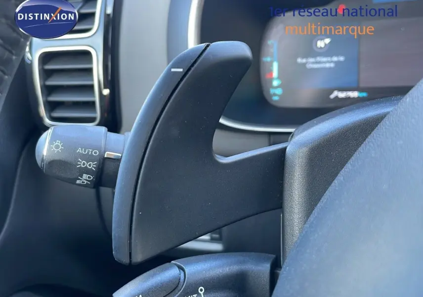 Gros plan sur la palette de changement de vitesses au volant d'un Citroën C5 Aircross blanc nacré hybride, tableau de bord en arrière-plan.