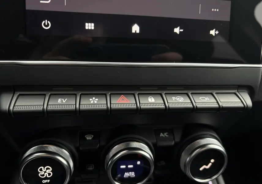 Gros plan sur la rangée de boutons de commande et les réglages de climatisation de la Renault Clio 2025 hybride noire.