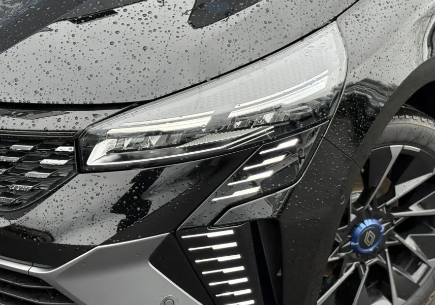 Gros plan sur l'avant droit noir étoilé de la Renault Clio 2025 avec phares LED et jante alliage distinctive.