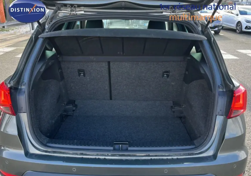 Coffre ouvert vu de l'arrière d'une SEAT Arona gris falaise métal, montrant l'espace de chargement vide.