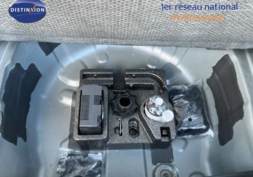 Vue plongeante sur le coffre ouvert d'un SEAT Arona gris falaise métal avec toit blanc, montrant le rangement d'outils intégré.