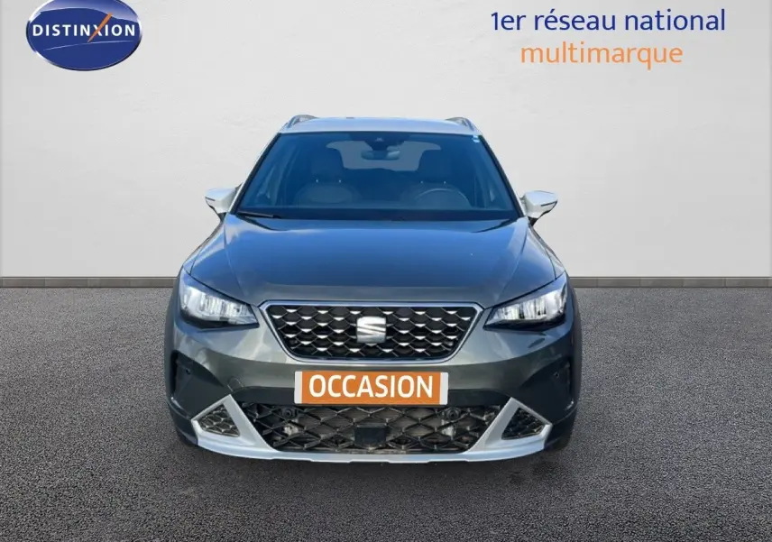 Vue frontale d'un SEAT Arona gris falaise métal avec toit blanc, calandre noire et plaque "OCCASION" orange.