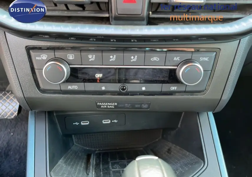 Vue rapprochée du tableau de bord et console centrale du SEAT Arona gris, montrant les commandes de climatisation et ports USB.