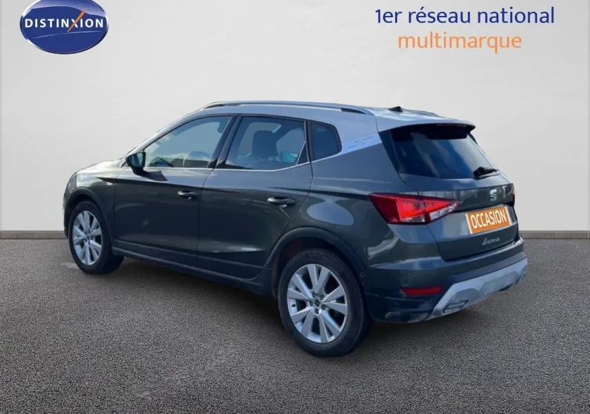 Vue 3/4 arrière gauche d'un SEAT Arona gris falaise métal avec toit blanc, version 2025 essence à boîte automatique.