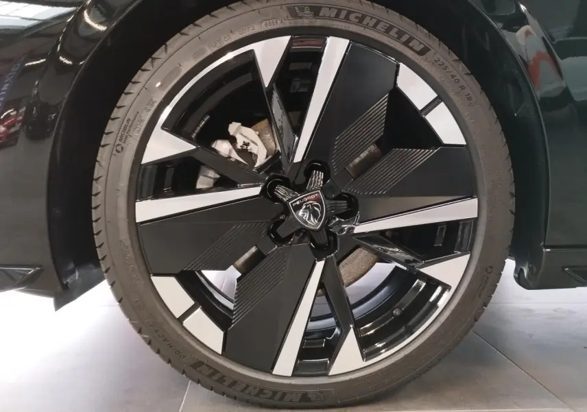 Gros plan sur la jante alliage 18 pouces bi-ton noir et argent de la Peugeot 308 noire métallisée, avec logo lion central.