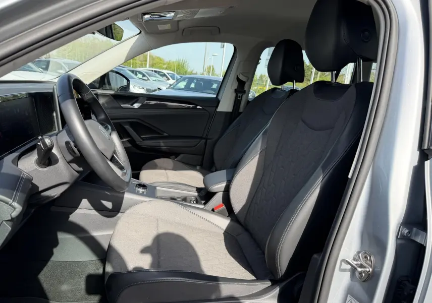 Vue intérieure côté conducteur du Volkswagen Tiguan 2025 gris, sièges tissu et cuir, volant multifonction cuir.