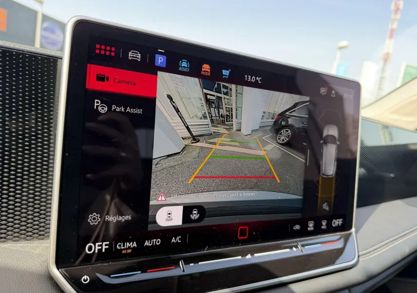 Écran tactile intérieur montrant l'assistance au stationnement avec vue caméra arrière du Volkswagen Tiguan gris.