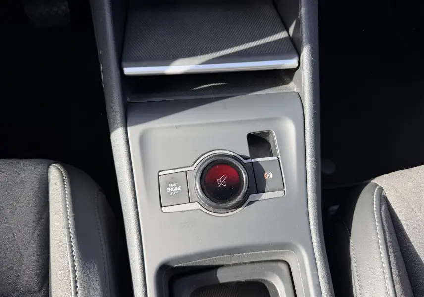 Gros plan sur la console centrale grise du Volkswagen Tiguan 2025, montrant le bouton Start/Stop et frein de stationnement électronique.