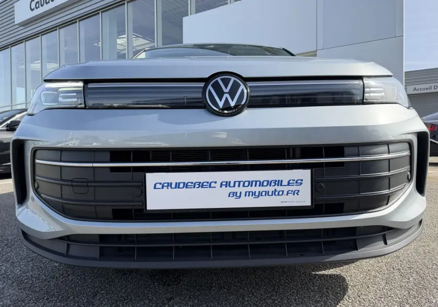 Vue frontale rapprochée du Volkswagen Tiguan gris 2025 avec calandre noire et logo VW central lumineux.