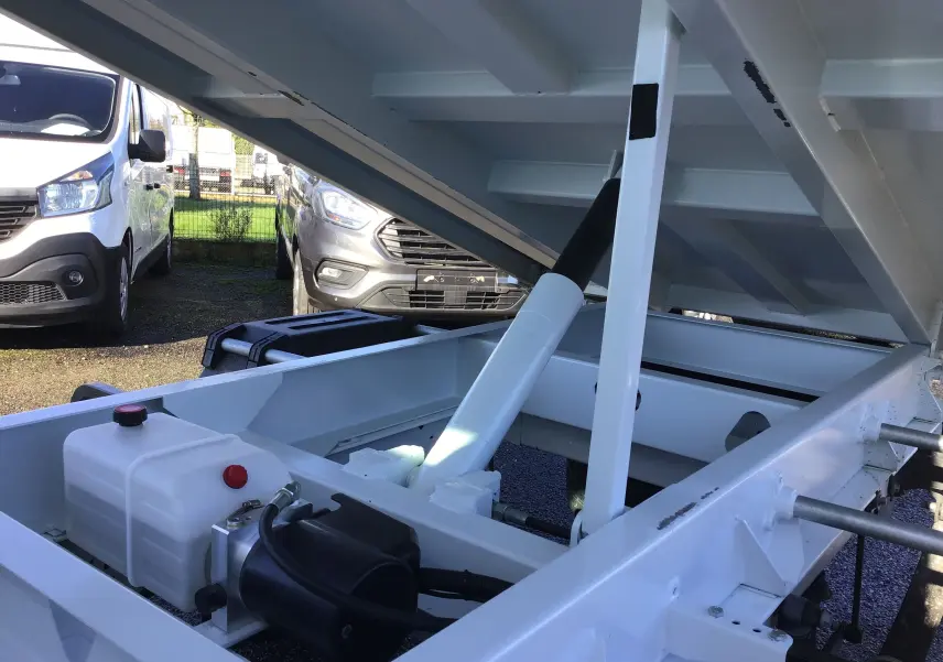 Vue rapprochée de la benne blanche relevée du Ford Transit Châssis Cabine 2024, montrant le vérin hydraulique et le châssis.