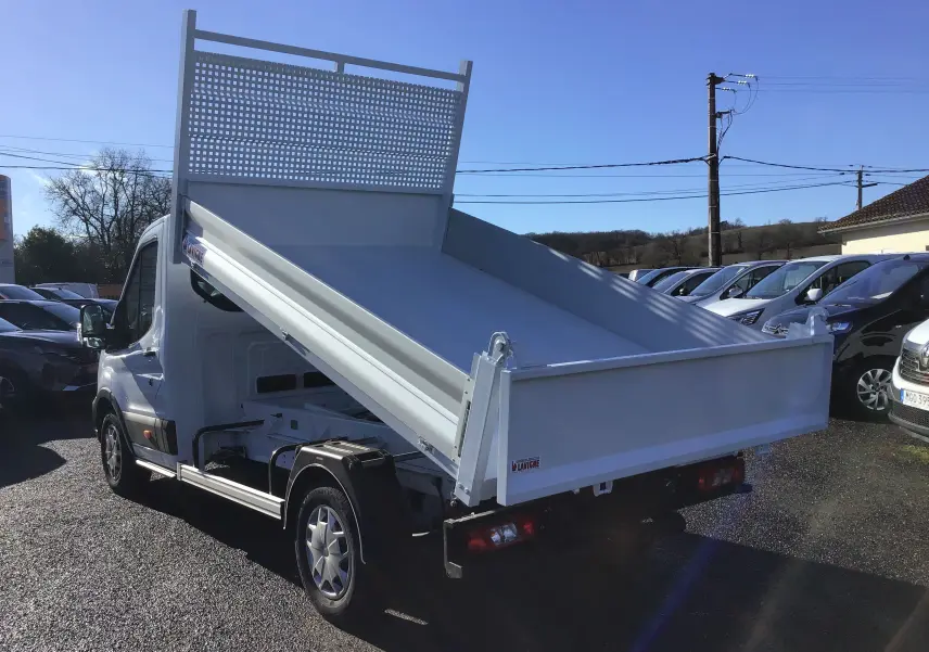 Ford Transit Chassis Cabine blanc vu en 3/4 arrière droit avec benne basculante relevée sur parking.