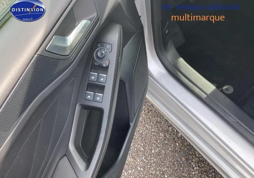 Vue rapprochée de la portière conducteur grise d'une Ford Focus 2025 avec commandes électriques des vitres et rétroviseurs.