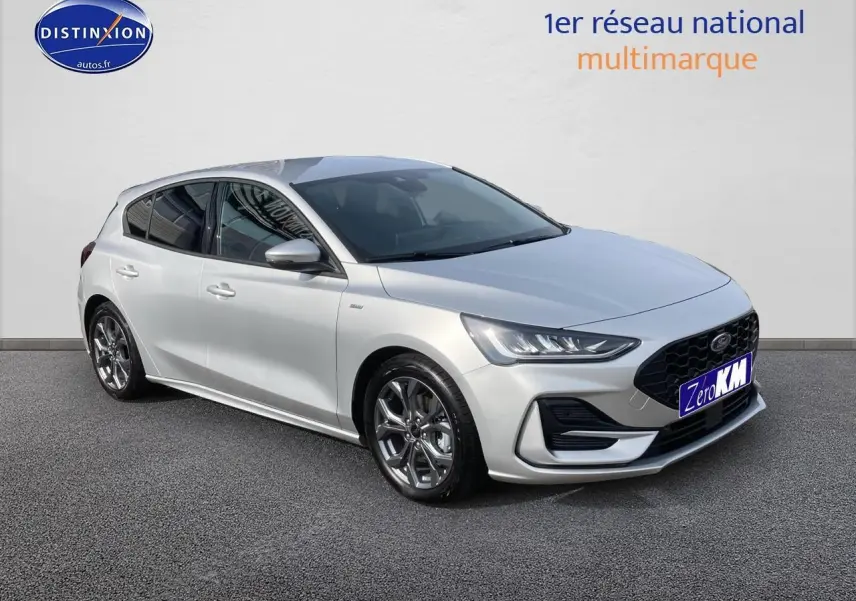 Ford Focus gris clair vue 3/4 avant droit avec jantes alu 17 pouces et calandre noire sportive.