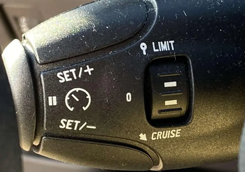 Gros plan sur la commande de régulateur de vitesse du Peugeot 208 noir, avec boutons SET, LIMIT et CRUISE visibles.