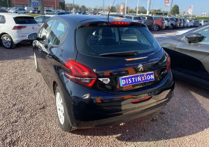 Peugeot 208 noire vue en 3/4 arrière droit, avec jantes blanches et plaque Distinxion visible.