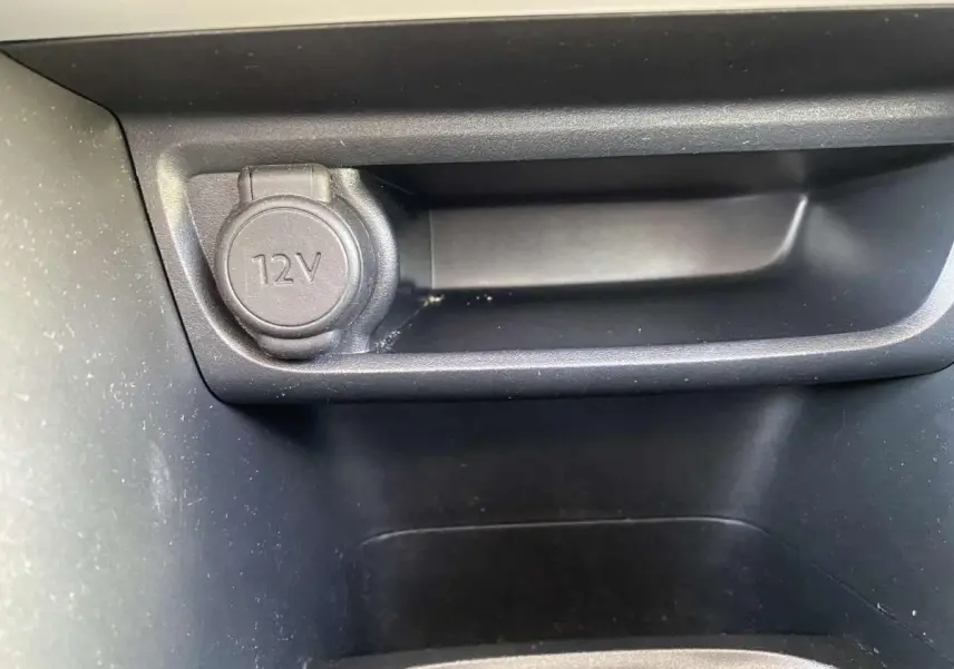 Prise 12V en gros plan dans la console centrale d'une Peugeot 208 noire essence de 2015.