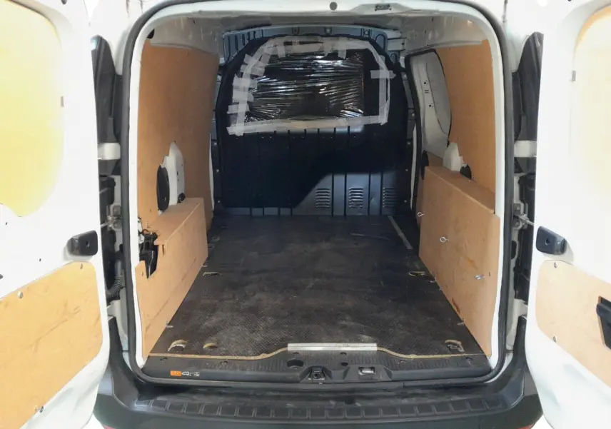Vue arrière intérieure du Renault Express Van blanc 2023, montrant l'espace de chargement avec panneaux en bois et sol noir antidérapant.