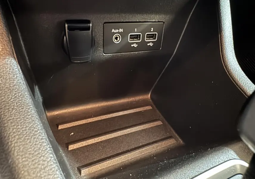 Gros plan sur la console centrale noire de la Renault Clio Business E-Tech hybride avec ports USB et prise Aux-IN.