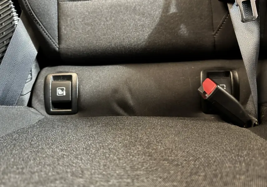 Gros plan sur la banquette arrière noire de la Renault Clio Business E-Tech hybride, montrant les boutons de rabattement et la ceinture de sécurité.