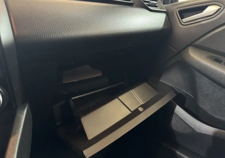 Vue intérieure côté passager de la boîte à gants ouverte sur tableau de bord noir texturé d'une Renault Clio Business E-Tech hybride.