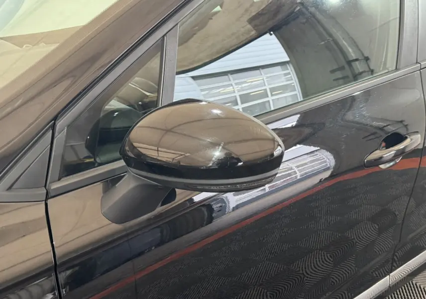 Gros plan sur le rétroviseur côté conducteur et la portière noire brillante d'une Renault Clio Business E-Tech hybride 2021.