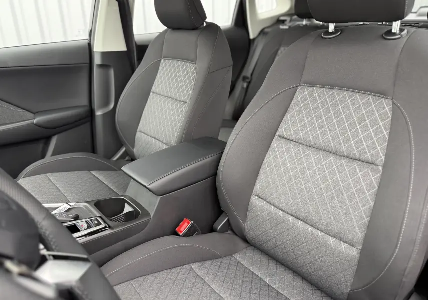 Vue intérieure rapprochée des sièges avant gris à motifs losanges du MG ZS 1.5L Hybrid+ 2026 avec accoudoir central noir.