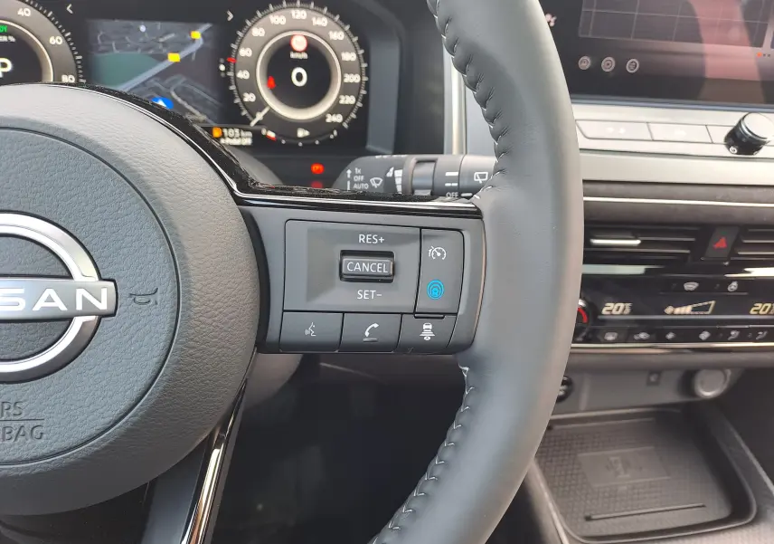 Gros plan sur le volant cuir noir du Nissan Qashqai 2025 avec commandes de régulateur et tableau de bord numérique.