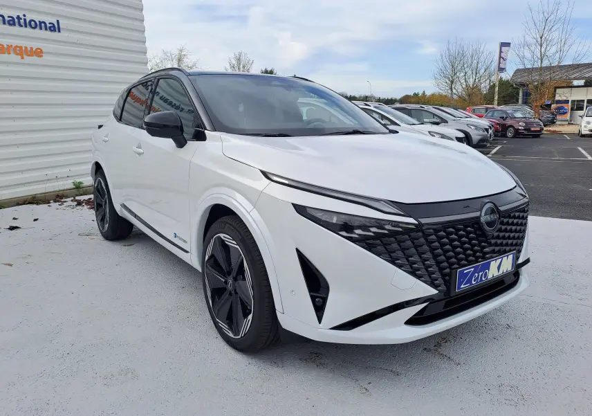 Nissan Qashqai 2025 blanc nacré et toit noir, vue 3/4 avant droit avec calandre noire distinctive.