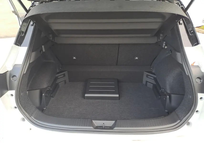 Coffre ouvert d'un Nissan Qashqai 2025 blanc nacré avec intérieur noir, montrant un espace de chargement propre et vide.