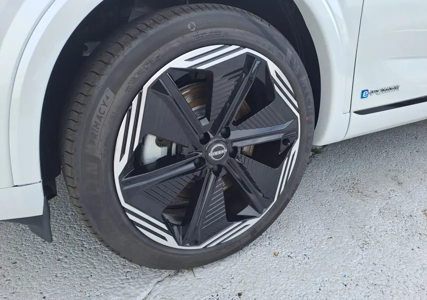 Gros plan sur la roue avant gauche du Nissan Qashqai blanc nacré avec jante noire et blanche au design moderne.