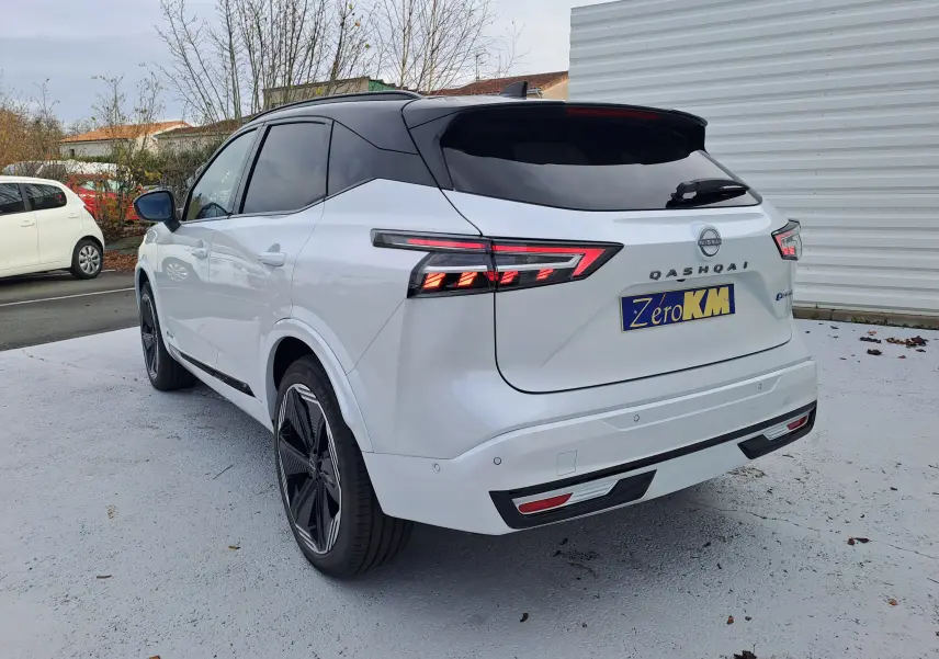 Vue 3/4 arrière droite du Nissan Qashqai blanc nacré avec toit noir, feux arrière LED et jantes noires design.