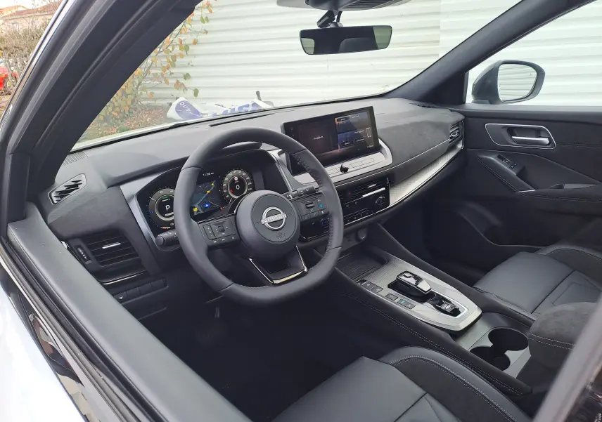 Intérieur noir du Nissan Qashqai 2025 vu côté conducteur, avec tableau de bord digital et écran tactile central.