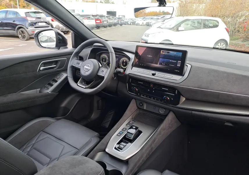 Intérieur noir du Nissan Qashqai 2025 vu côté conducteur, avec tableau de bord moderne et écran tactile central.