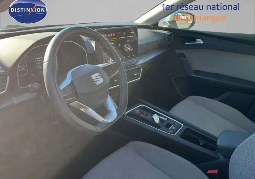 Vue intérieure côté conducteur de la SEAT LEON 2025, mettant en valeur le volant multifonction et la console centrale moderne.