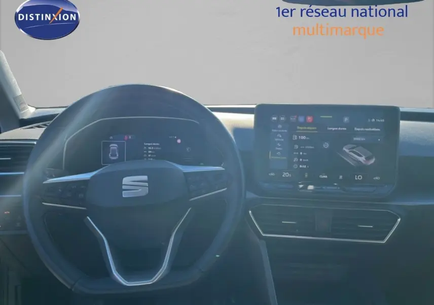 Vue intérieure centrée sur le volant et l’écran tactile du tableau de bord d’une SEAT LEON gris magnétique 2025.