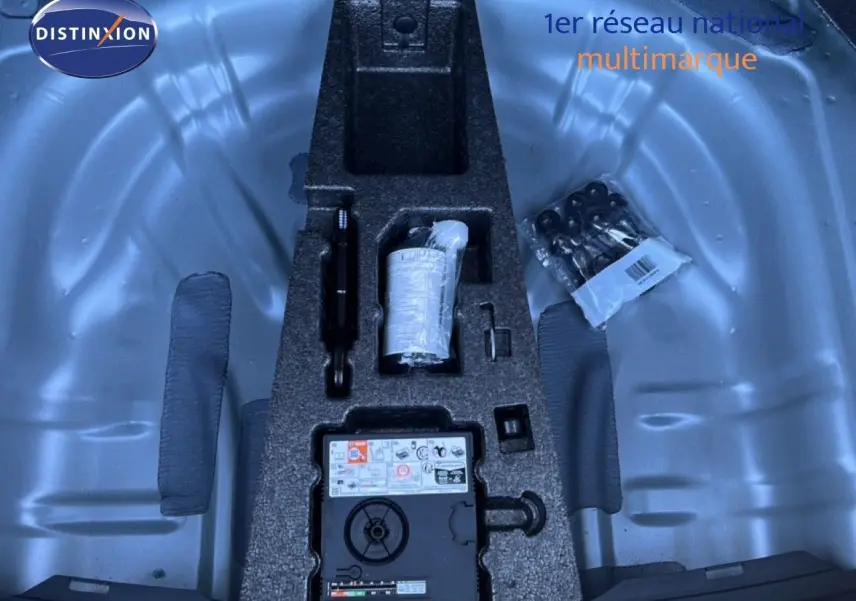 Vue plongeante sur le coffre d’un SEAT Leon gris métallique, montrant le rangement d’outils et kit de réparation.