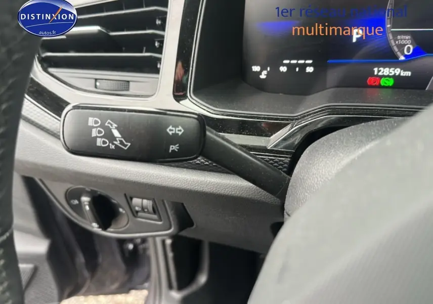 Gros plan sur le commodo gauche et le tableau de bord numérique d'une Volkswagen Polo gris cendre, intérieur noir.