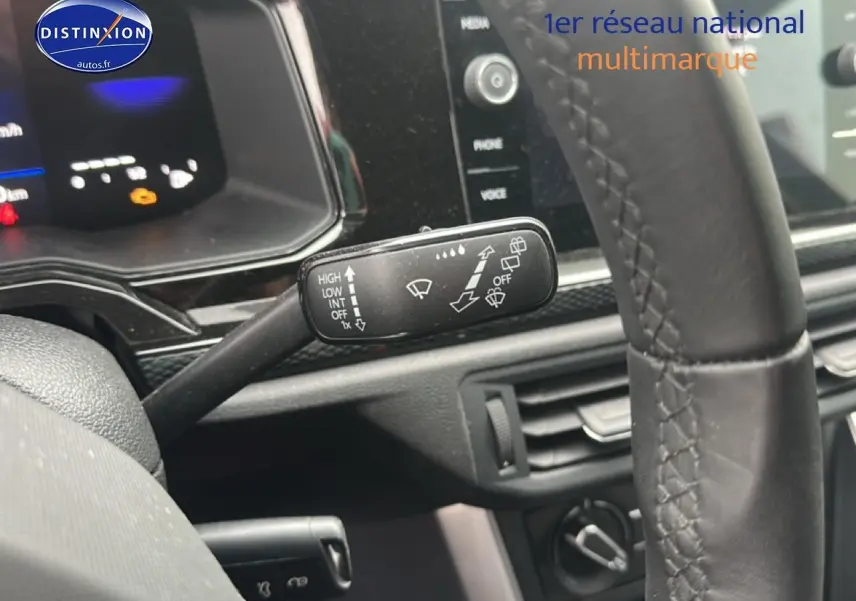 Gros plan sur la commande d’essuie-glace à gauche du volant cuir d’une Volkswagen Polo gris cendre, tableau de bord noir.