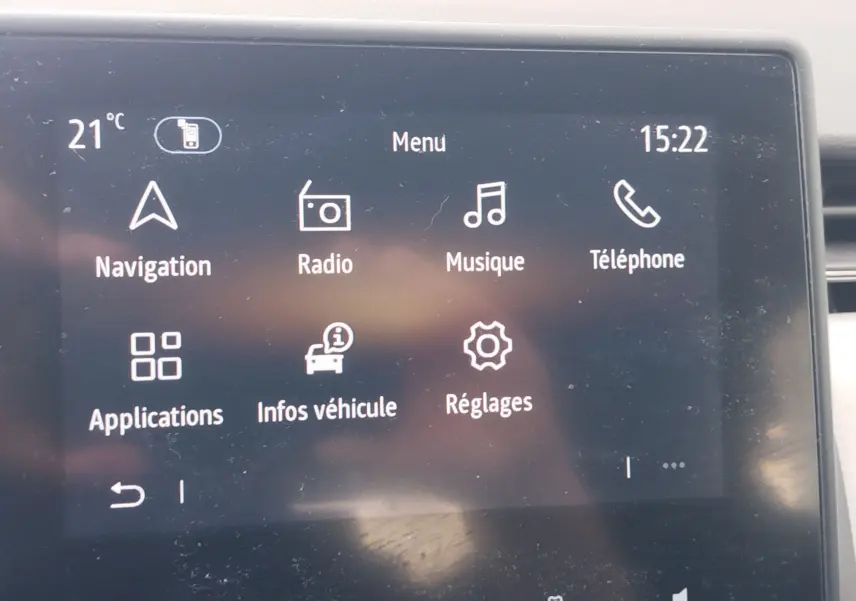 Écran tactile central de la Renault Clio 2022 affichant le menu principal avec options navigation, radio, musique et téléphone.