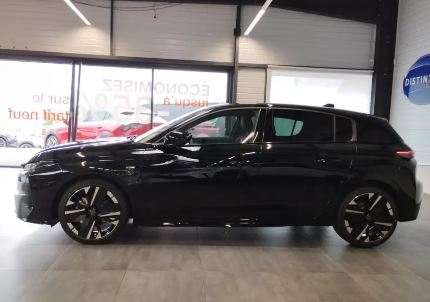 Profil côté gauche d'une Peugeot 308 noire métallisée avec jantes alliage bi-tons et blason distinctif sur l'aile avant.