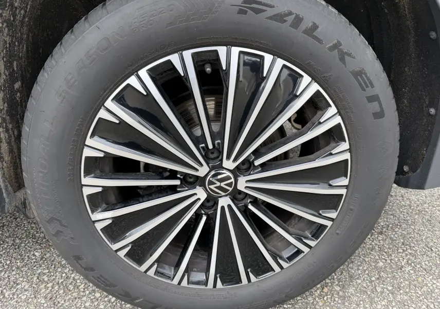 Gros plan sur la jante alliage bicolore noire et argentée avec logo Volkswagen au centre du Volkswagen Tiguan blanc.