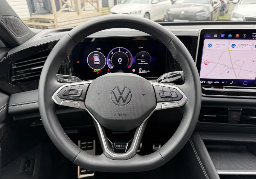 Vue intérieure centrée sur le volant cuir multifonction et l'écran numérique du Volkswagen Tiguan blanc 2025.